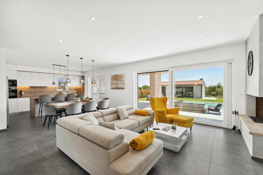 Ljust vardagsrum med utgång till terrassen och utsikt över poolen