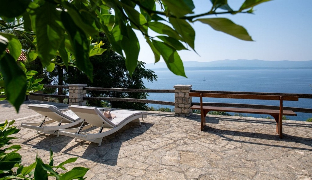 Stenterrass med solstolar och panoramautsikt över havet
