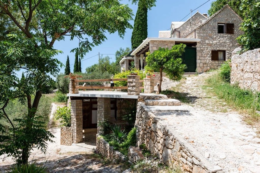 Stenhus på en sluttning med trädgård och terrass