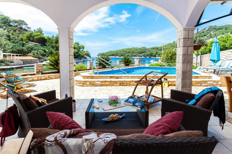 Täckt terrass med utsikt över poolen och havet