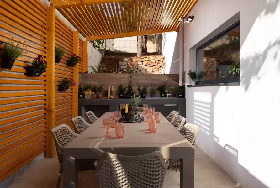 Sommarkök under tak med matbord och pergola