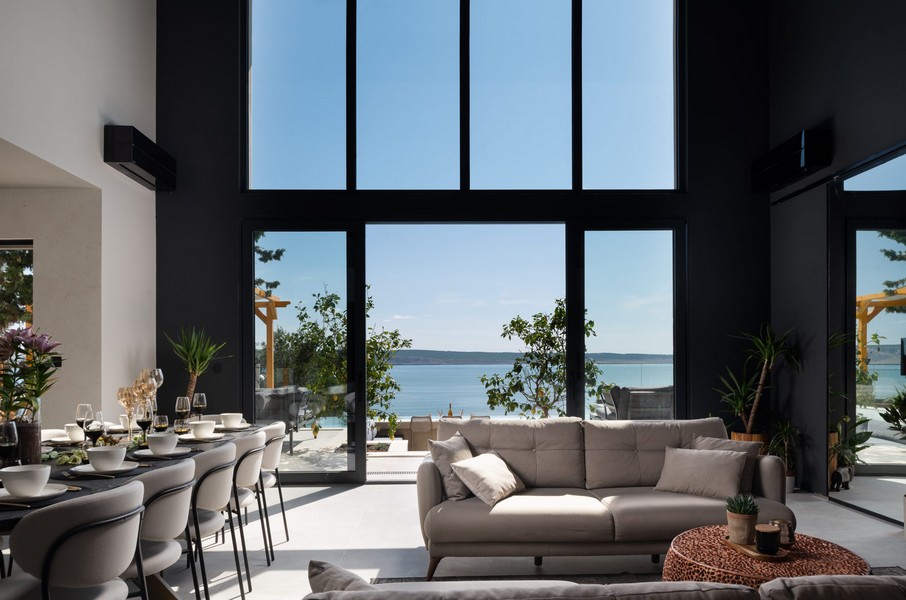 Vardagsrum med stora panoramafönster och havsutsikt