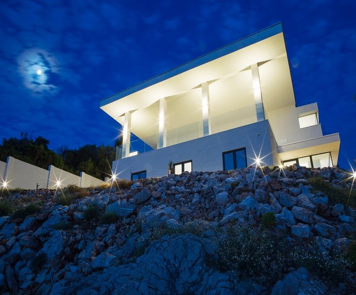 Modern villa nära Dubrovnik precis vid havet på natten med belysning