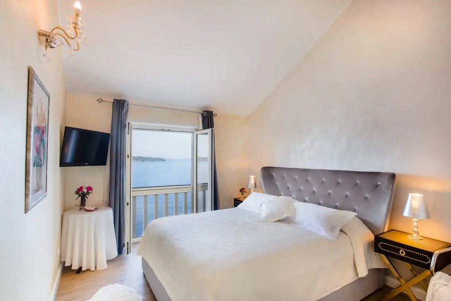 Ljust sovrum med dubbelsäng och balkong mot havet