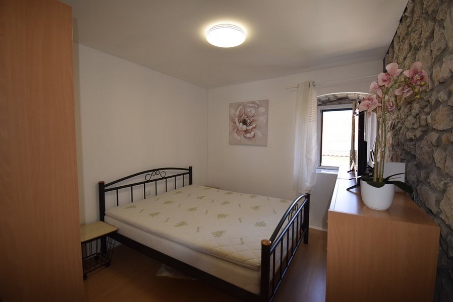 Ljust sovrum med dubbelsäng och stenvägg