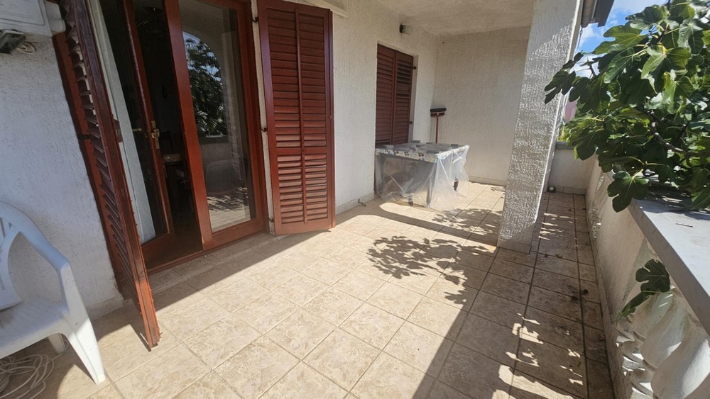 Övertäckt terrass med klinkergolv och träluckor