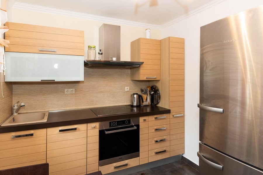 Modernt utrustat kök med träfronter och rostfritt kylskåp