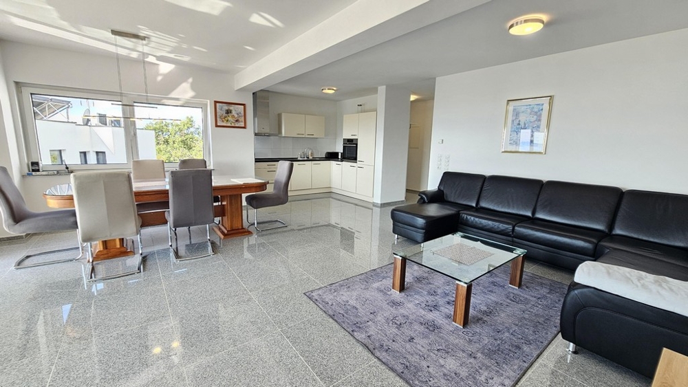 Ljust vardagsrum med matplats och kök