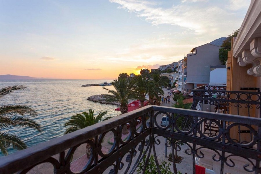 Balkong med havsutsikt och strandpromenad vid solnedgången