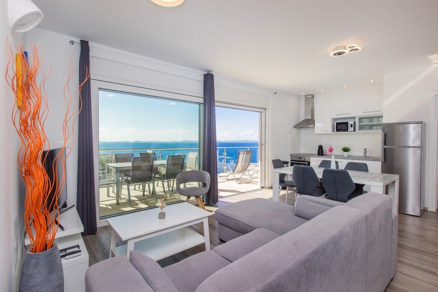 Vardagsrum med kök och tillgång till terrassen med havsutsikt