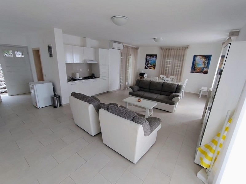 Ljust vardagsrum med öppet kök och soffor