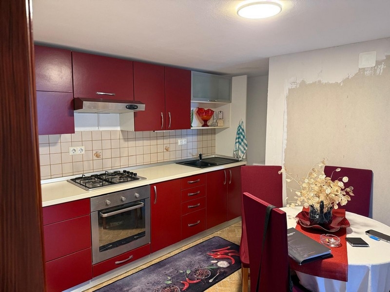 Kök med röda inbyggda möbler och matplats