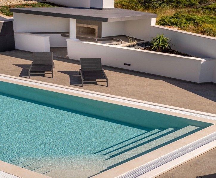 Poolområde med solstolar och modernt sommarkök