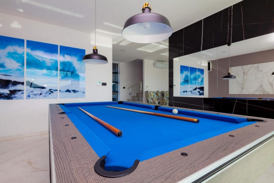 Vardagsrum med modernt biljardbord och stilren belysning