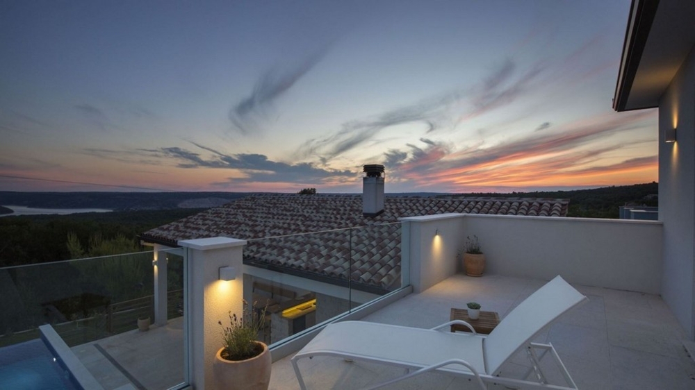 Villans terrass med solstolar och panoramautsikt vid solnedgången
