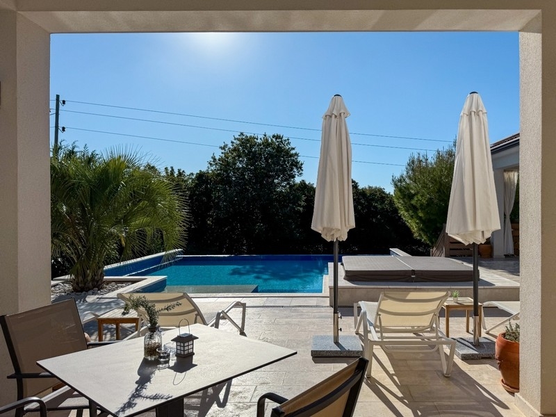 Täckt terrass med sittgrupp och utsikt över poolen