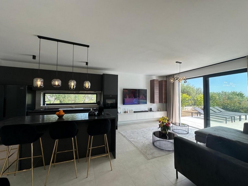 Modernt kök med matplats och utsikt över terrassen.