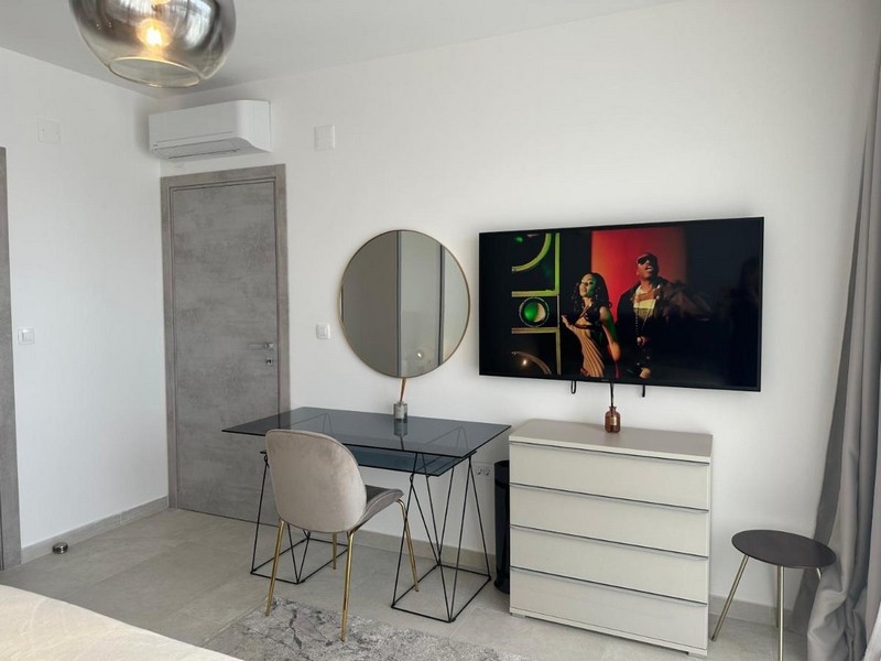 Modernt inrett sovrum med skrivbord, spegel och TV