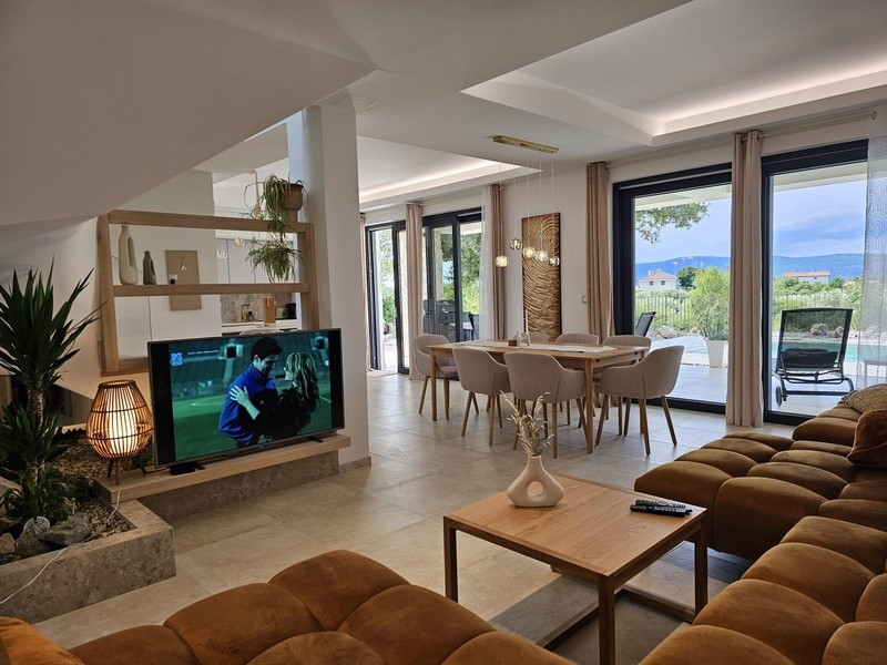 Ljust vardagsrum med matplats och utsikt över poolen