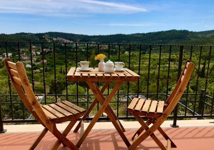Balkong med bord och stolar, utsikt över kullarna
