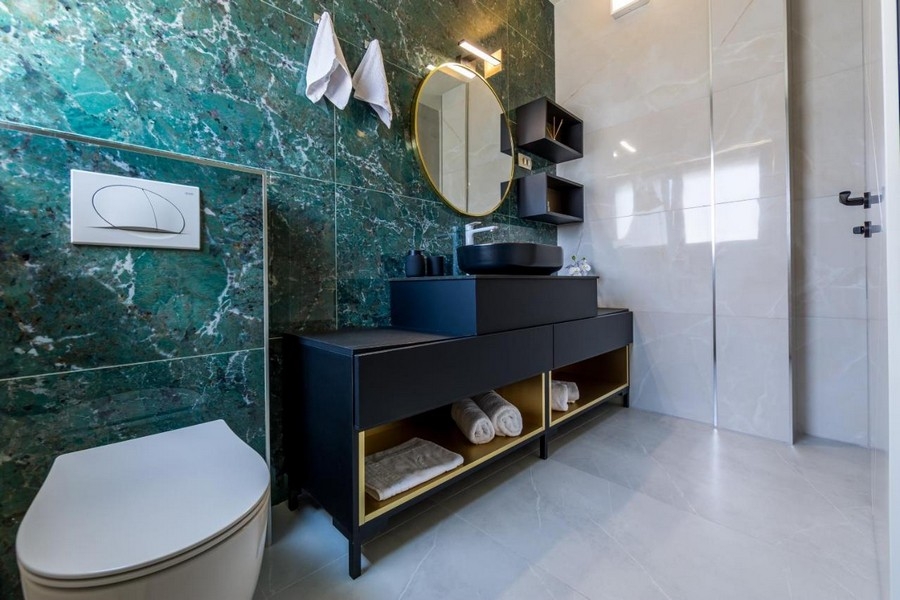 Badrum med grön marmorvägg och modernt handfat