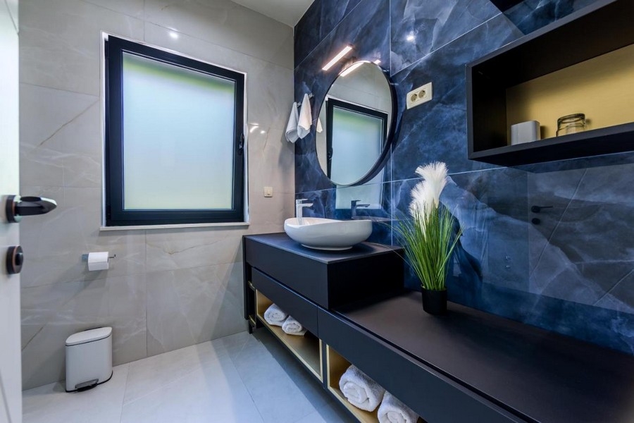 Badrum med blå marmorvägg och rund spegel