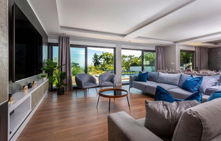 Ljust vardagsrum med stort fönsterfront och utsikt över altanen