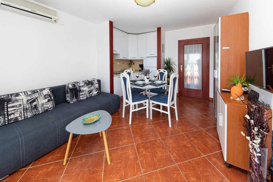 Vardagsrum med vitt kök och matplats