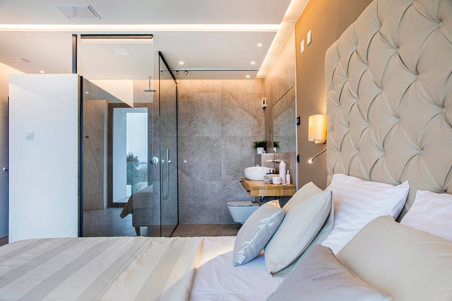 Sovrum med badrum i glas och beige sänggavel.