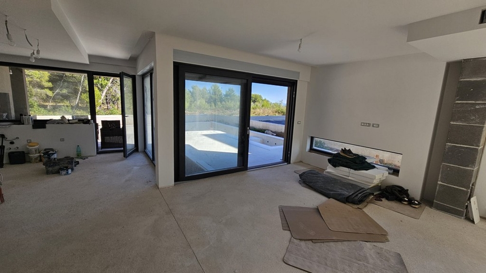 Vardagsrum i råbyggnad med glasfront mot poolen - villa H3778 i Privlaka.