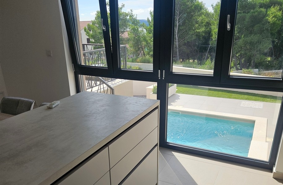 Köksdel med utsikt över poolen och trädgården