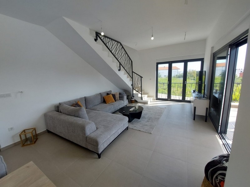 Ljust vardagsrum med soffa och trappa