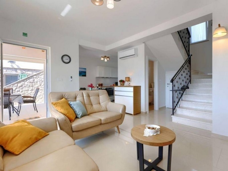 Vardagsrum med soffa, trappa och tillgång till terrassen