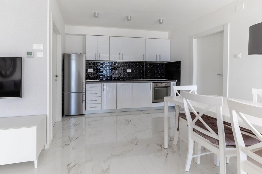 Modernt kök med vitt utrustat kök och matplats