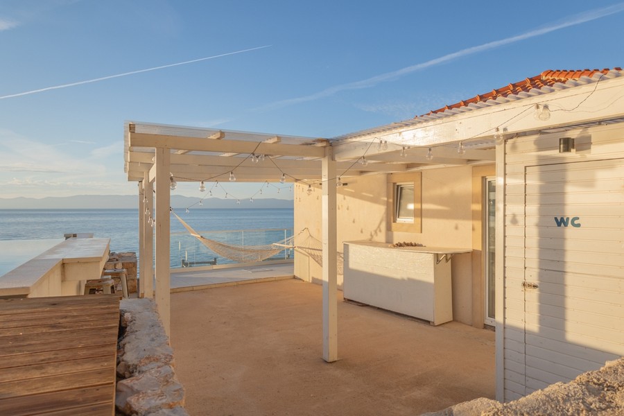 Täckt terrass med utomhusbar och havsutsikt