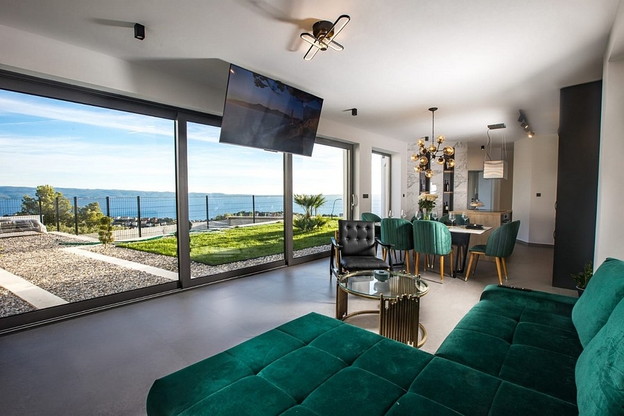 Modernt vardagsrum med stora glasfronter och havsutsikt