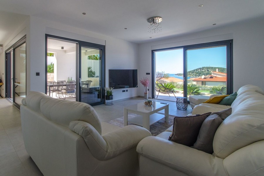 Ljust vardagsrum med stor glasfront och havsutsikt