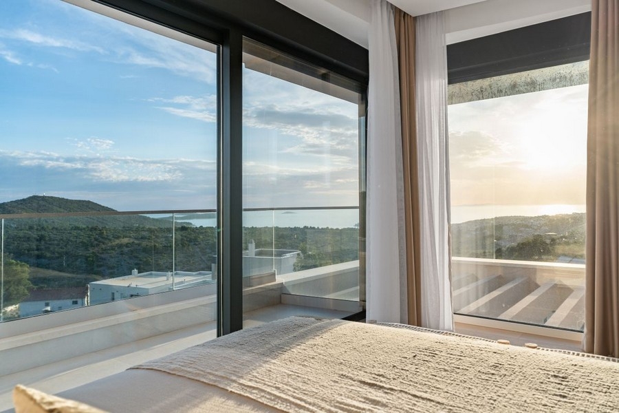 Sovrum med fönster från golv till tak och panoramautsikt över havet