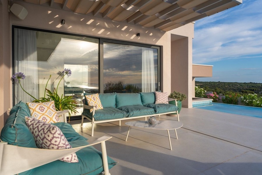 Täckt terrass med lounge och utsikt över poolen och havet