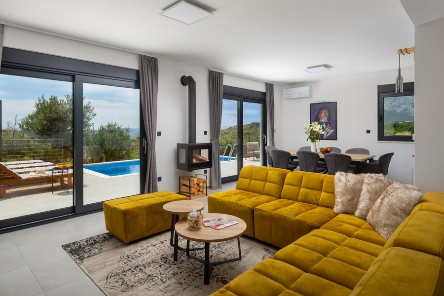 Vardagsrum med soffa, öppen spis och tillgång till poolterrassen