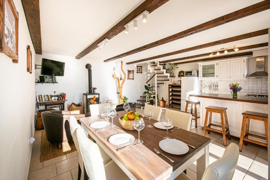 Vardagsrum med träbjälkar, öppen spis och kök