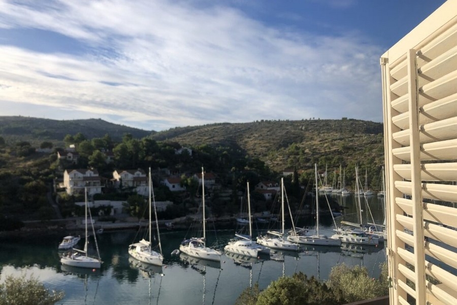 Havsutsikt från balkong med segelbåtar i bukten