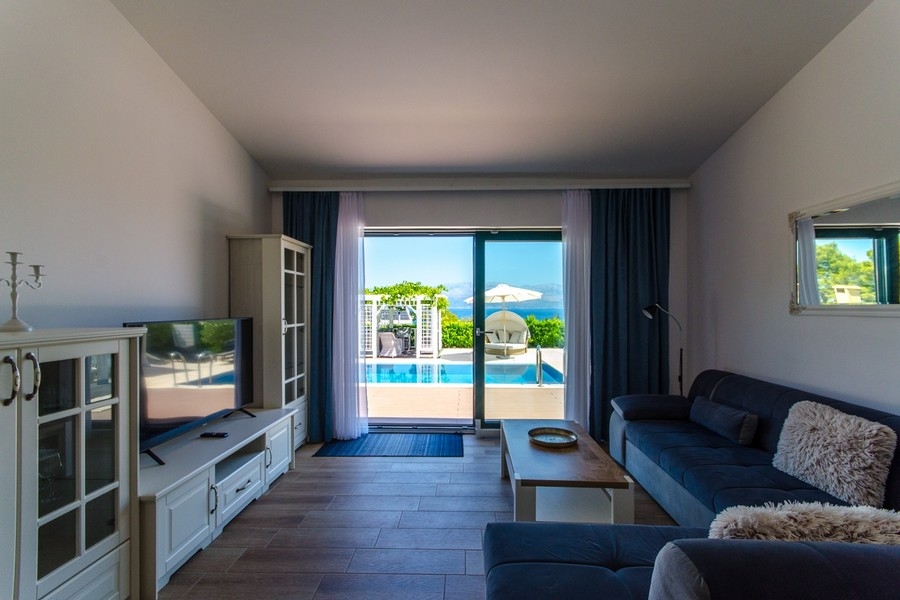 Vardagsrum med utgång till terrassen och utsikt över poolen