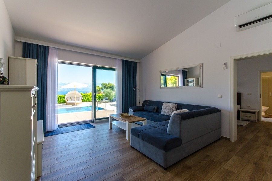 Vardagsrum med soffa och altandörr till poolen