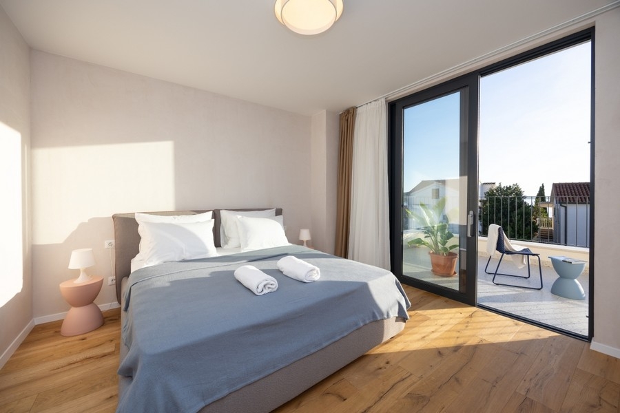 Sovrum med dubbelsäng och tillgång till terrassen på Villa H3837 i Rogoznica, Kroatien.