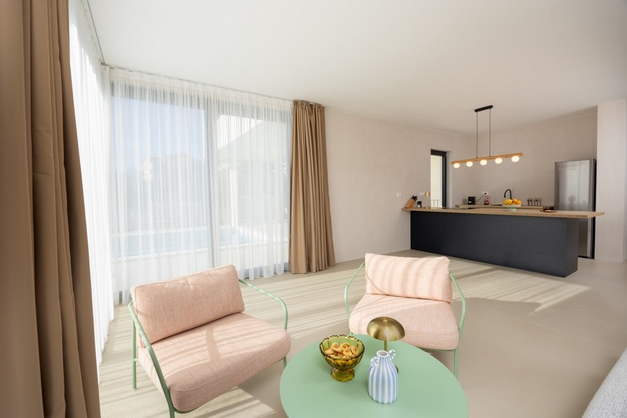 Öppet vardagsrum med kök och stora fönster