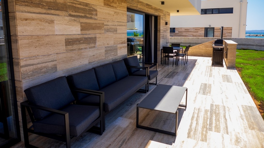 Täckt terrass med lounge och grillplats