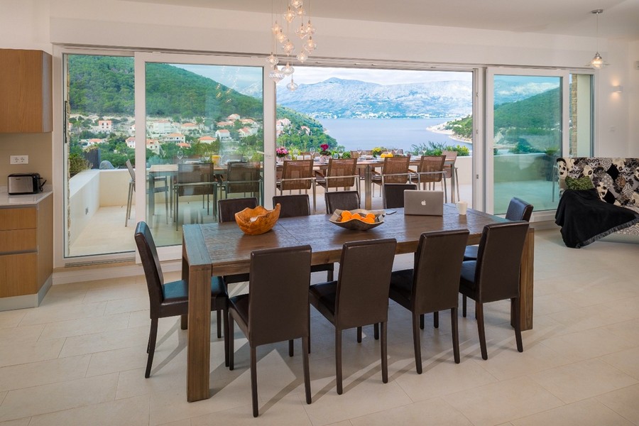 Vardagsrum med stort matbord och panoramafönster med havsutsikt