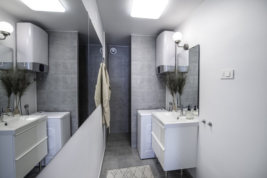 Modernt badrum med tvättmaskin och handfat