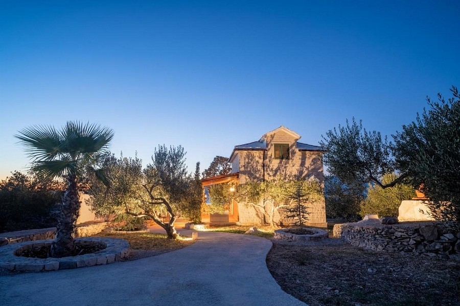 Dalmatisk hus i kvällsatmosfär med upplyst trädgård